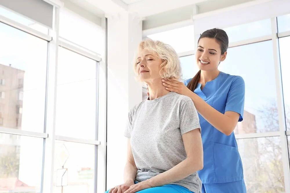 A Nurse Is Giving An Elderly Woman A Massage In A Hospital — Southern Districts Physiotherapy & Sports Injuries Clinic In Albion Park, NSW