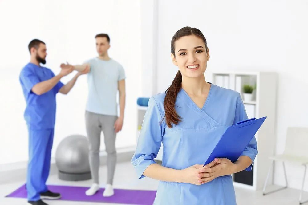 A Female Nurse Is Holding A Clipboard In Front Of A Group Of People — Southern Districts Physiotherapy & Sports Injuries Clinic In Albion Park, NSW