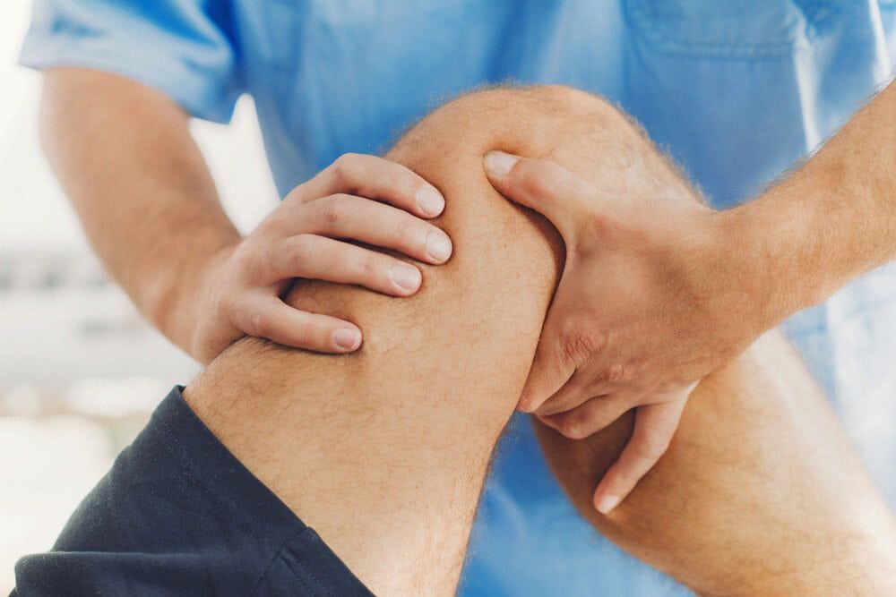 A Man Is Getting His Knee Examined By A Doctor — Southern Districts Physiotherapy & Sports Injuries Clinic In Tullimbar, NSW