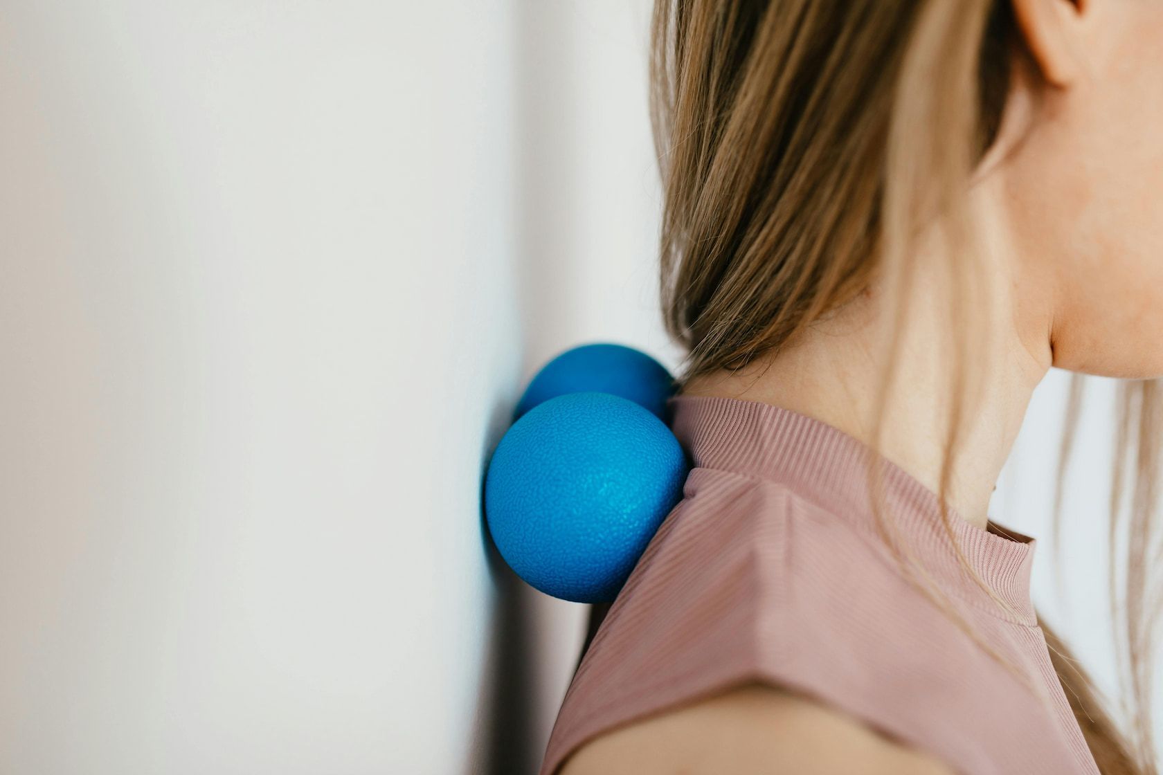 A Woman Is Using A Massage Ball Against A Wall — Southern Districts Physiotherapy & Sports Injuries Clinic In Albion Park, NSW