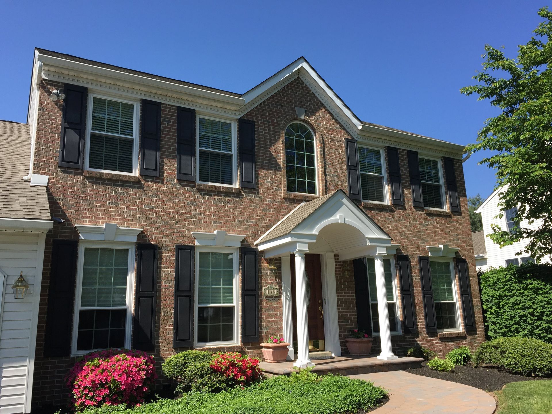 A large brick house with black shutters on the windows