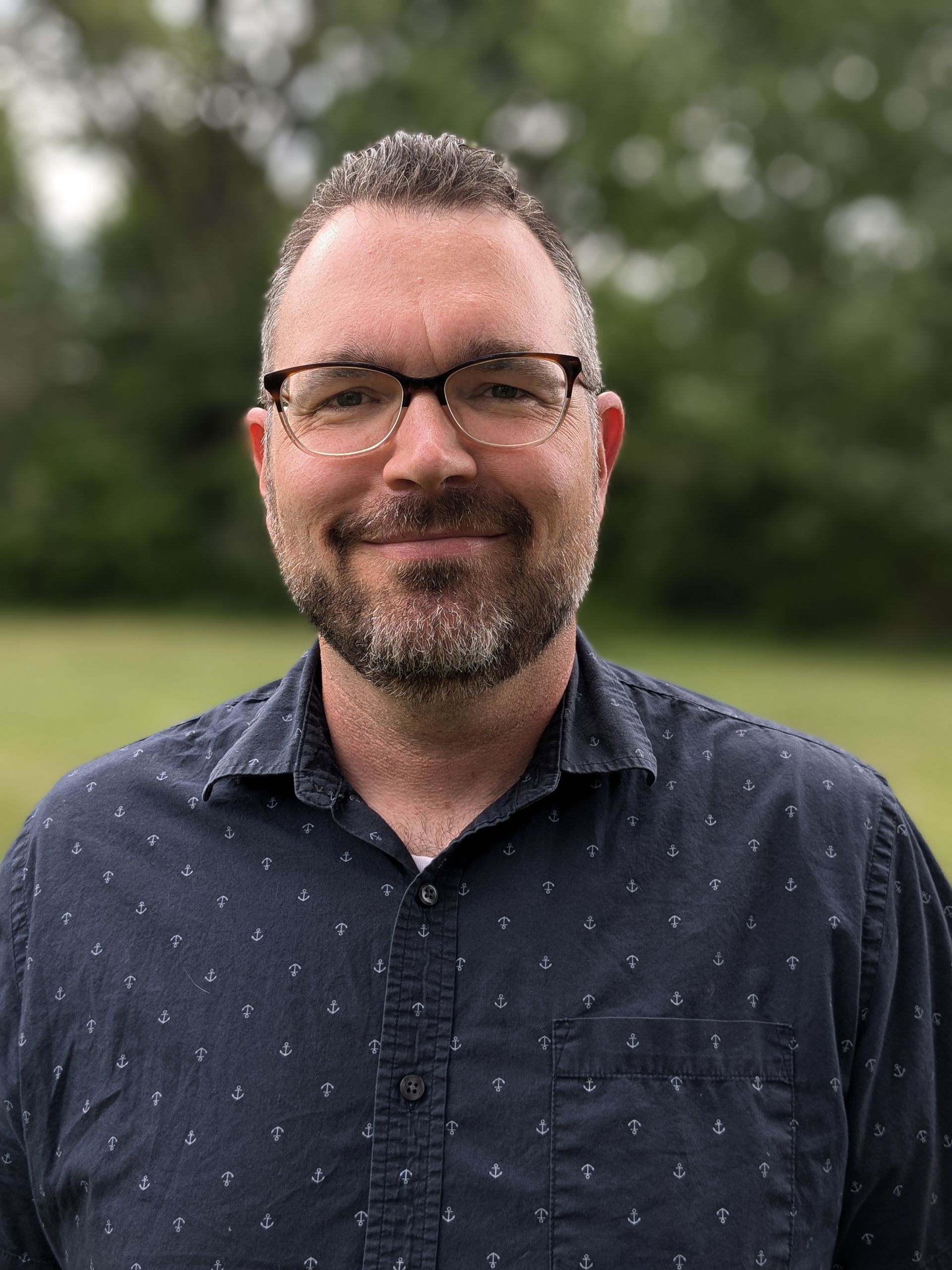 A man wearing glasses and a blue shirt is taking a selfie in a field in Doylestown, PA.