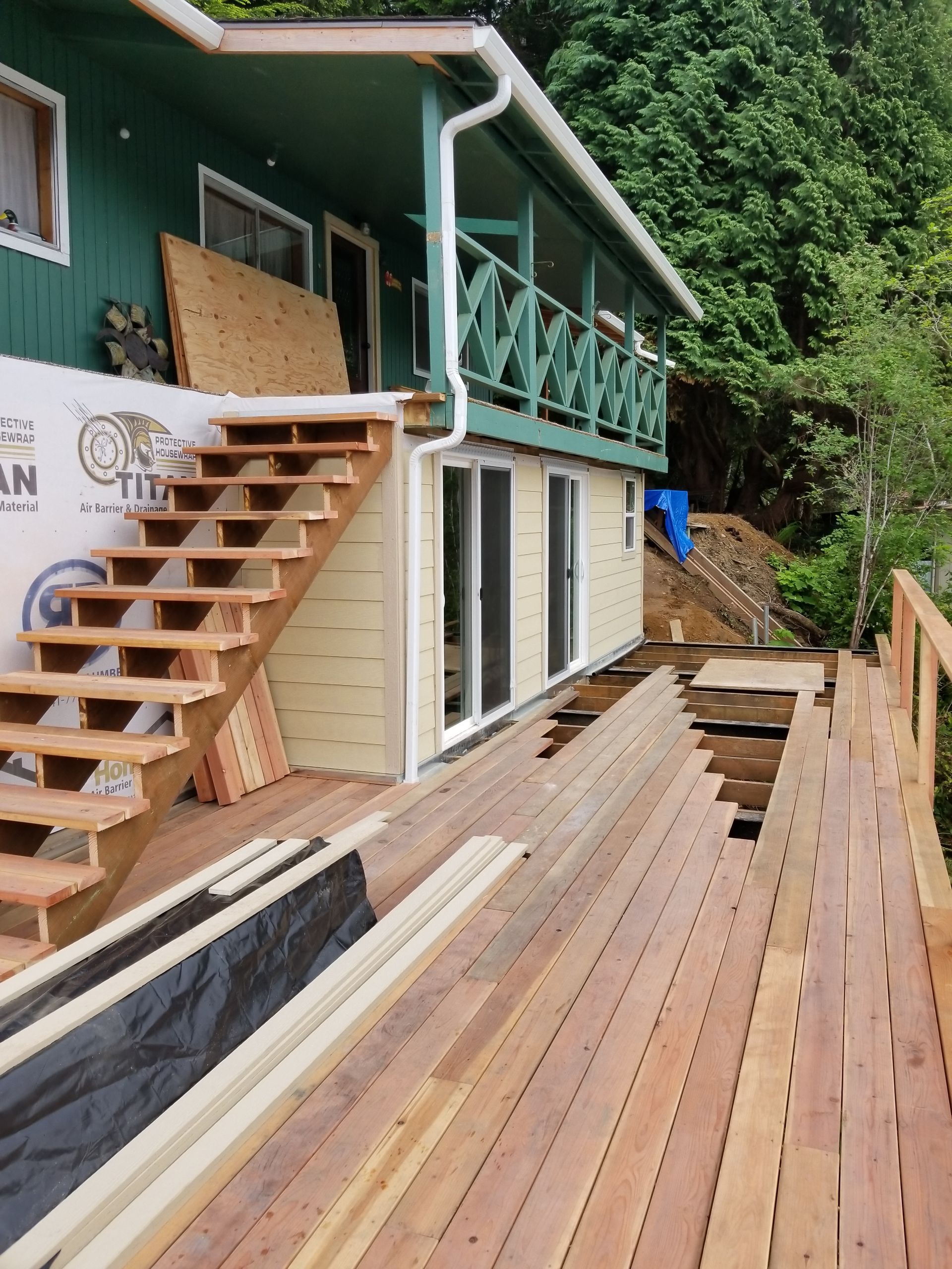 House with a deck under construction; stairs lead to an upper balcony.
