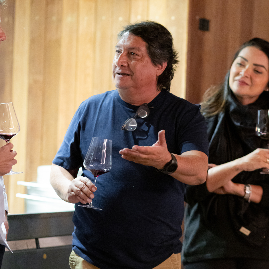 Um homem de chapéu está bebendo uma taça de vinho.
