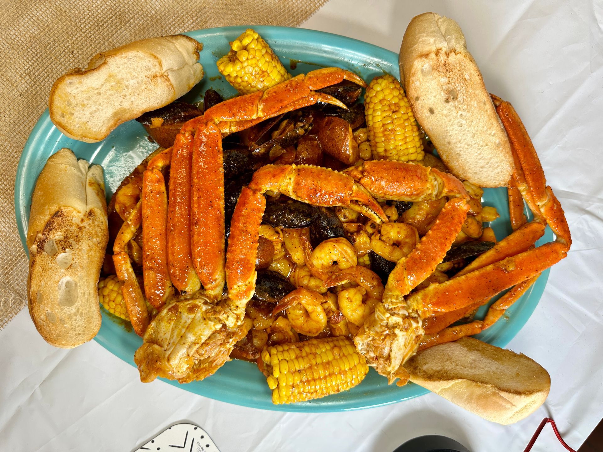 Seafood boil on blue plate with crab legs, corn, shrimp, and bread.