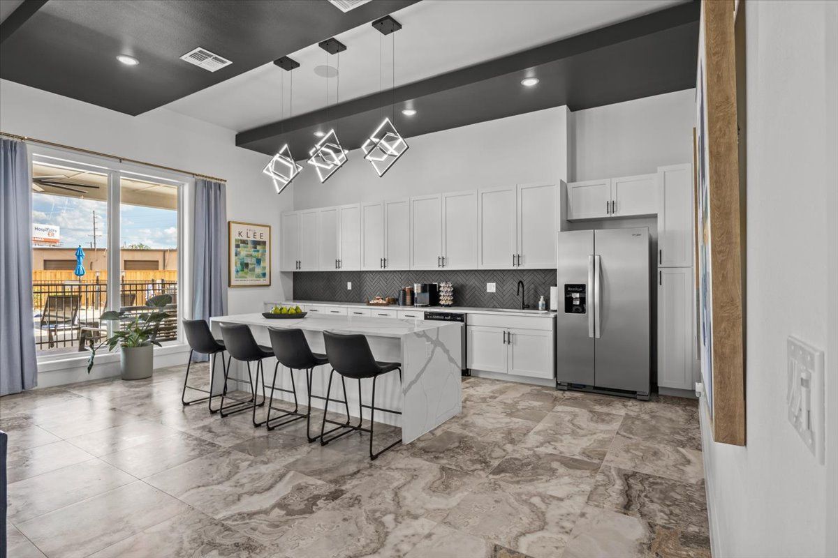 Modern kitchen with white cabinets, island, and stainless steel appliances.