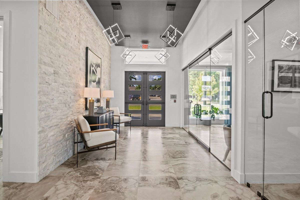 Interior hallway with stone wall, glass doors, and modern light fixtures.