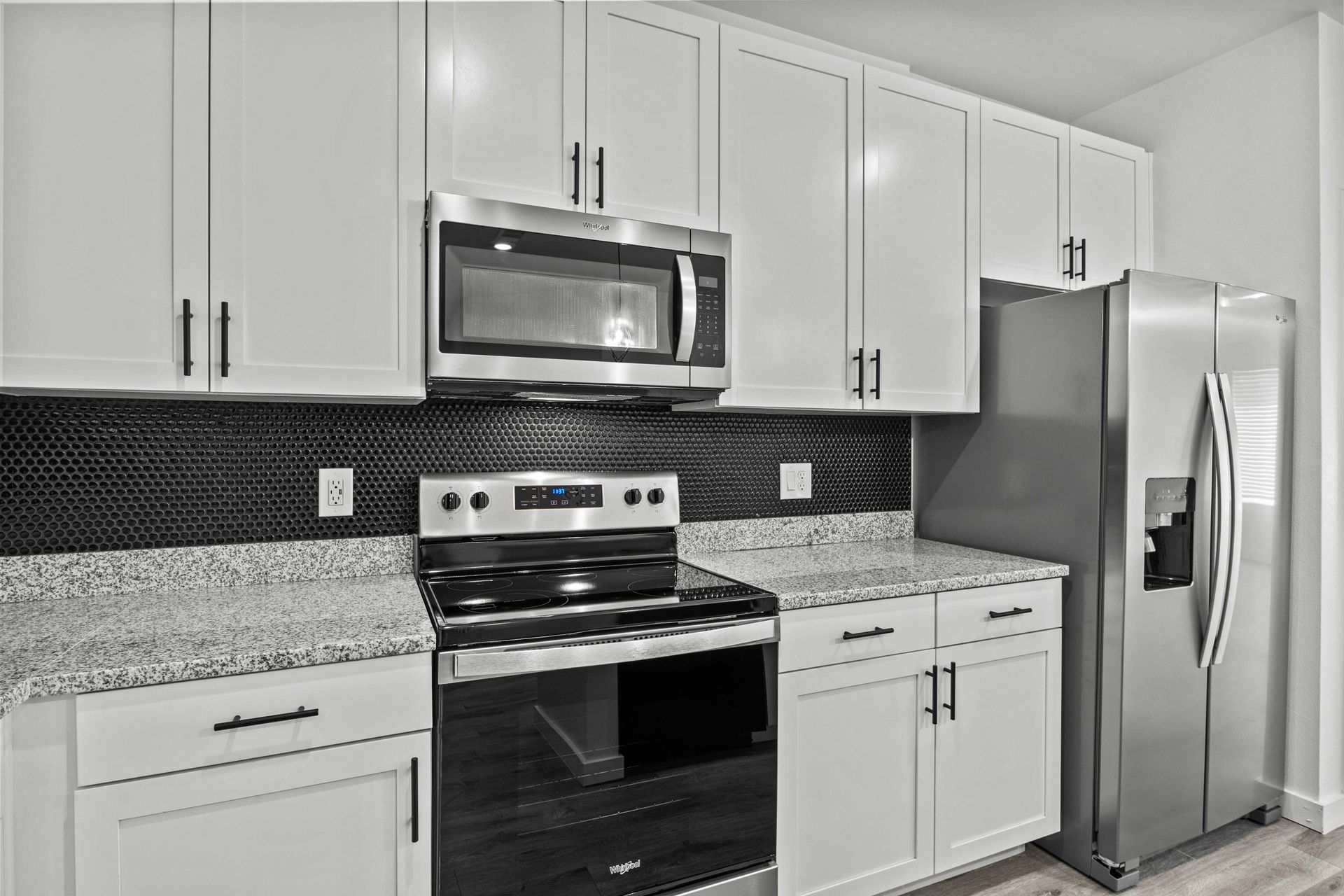 White kitchen cabinets, stainless steel appliances, and granite countertops.