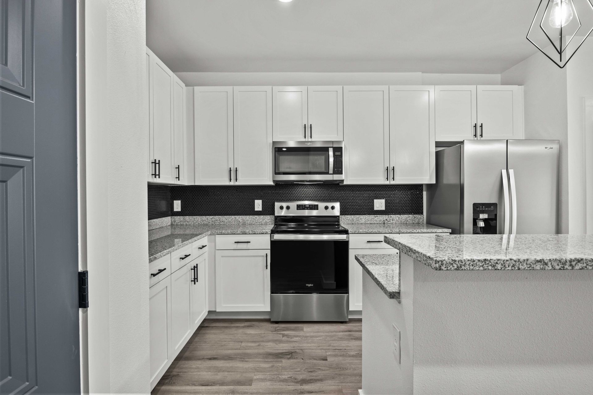 Modern kitchen with white cabinets, stainless steel appliances, and gray countertops.