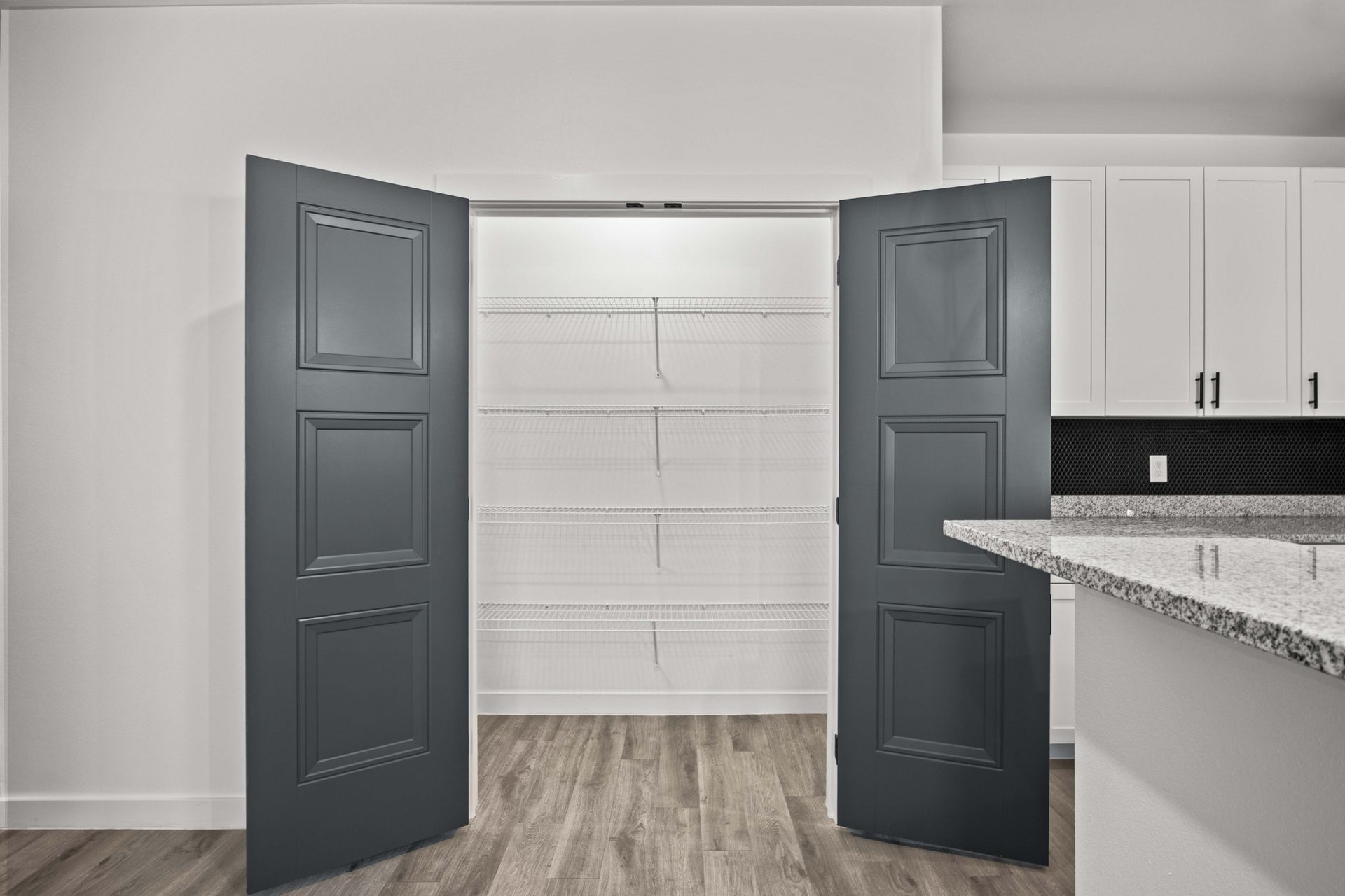 Gray pantry doors open to reveal white wire shelving.
