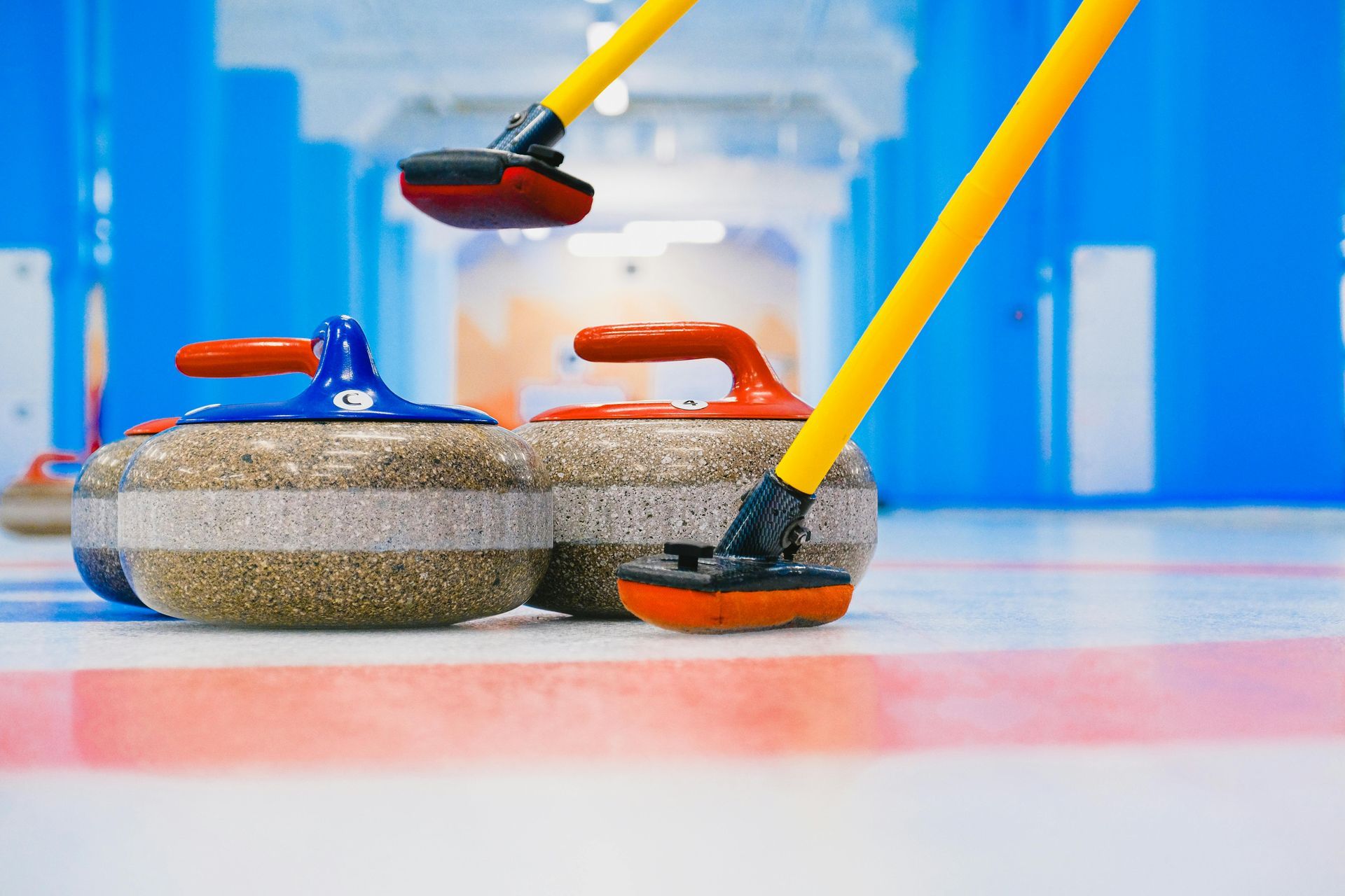 A group of curling stones with sticks on a rink.