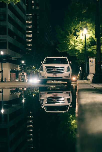 A white car is parked on the side of the road at night.