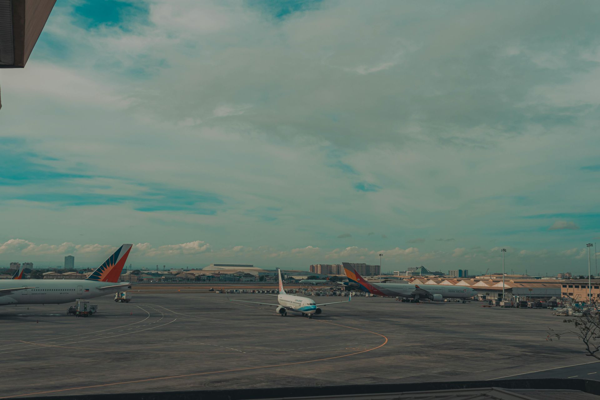 A row of airplanes are parked on a runway at an airport.