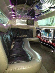 The inside of a limousine with a couch and a television.