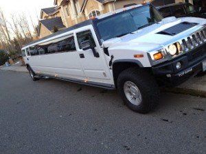 A white hummer limousine is parked on the side of the road.