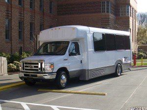A white van is parked in front of a brick building