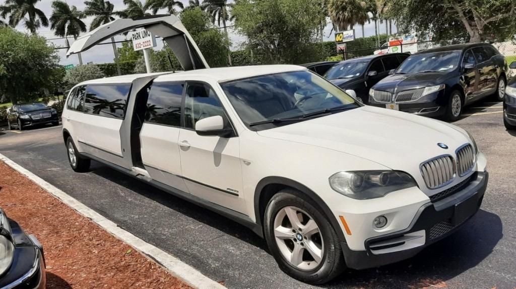 A white limousine is parked in a parking lot.