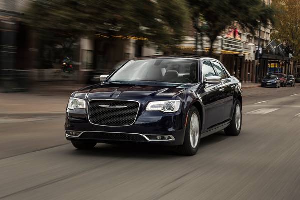 A blue chrysler 300 is driving down a city street.