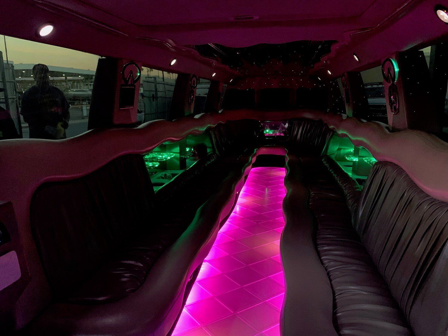 The inside of a limousine with pink and green lights.