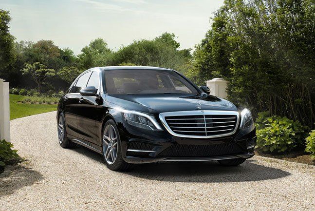 A black mercedes benz s class is parked on a gravel driveway.