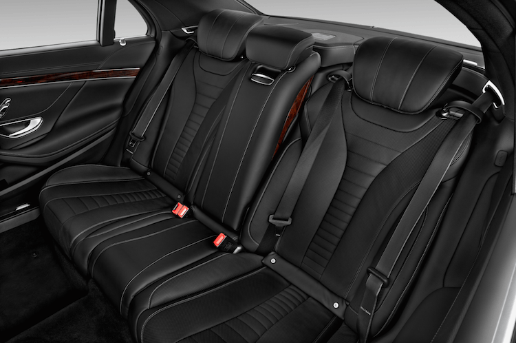 The back seats of a car with seat belts.