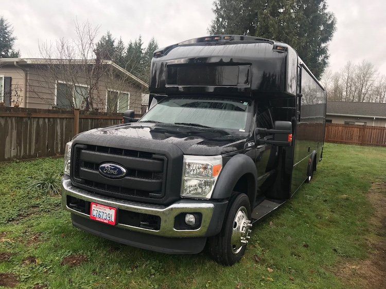 A black ford truck is parked in a grassy yard in front of a house.