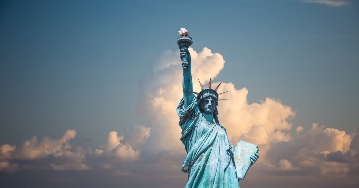 The statue of liberty is standing in front of a cloudy sky.