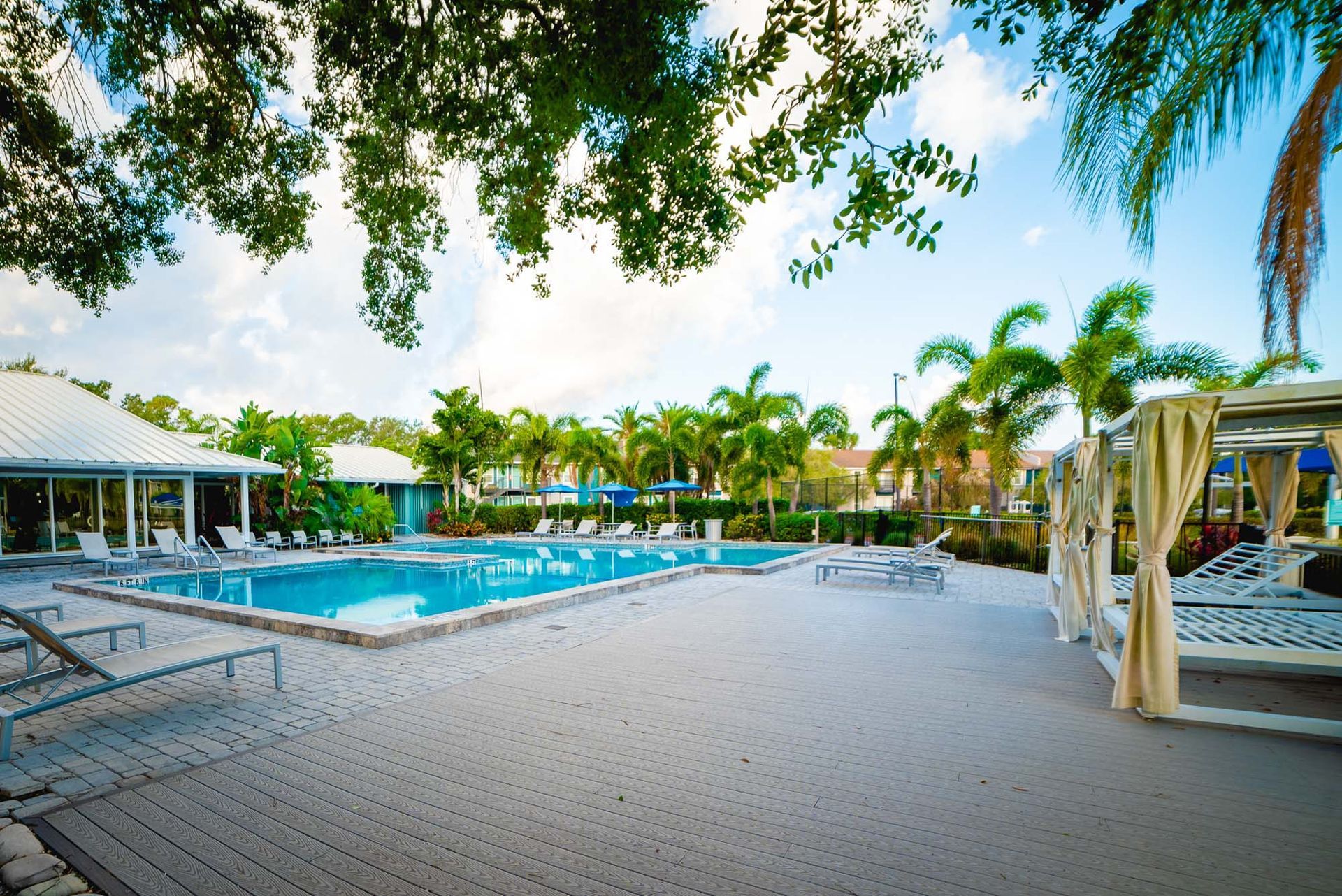 A large swimming pool surrounded by palm trees and chairs at Trellis at The Lakes.