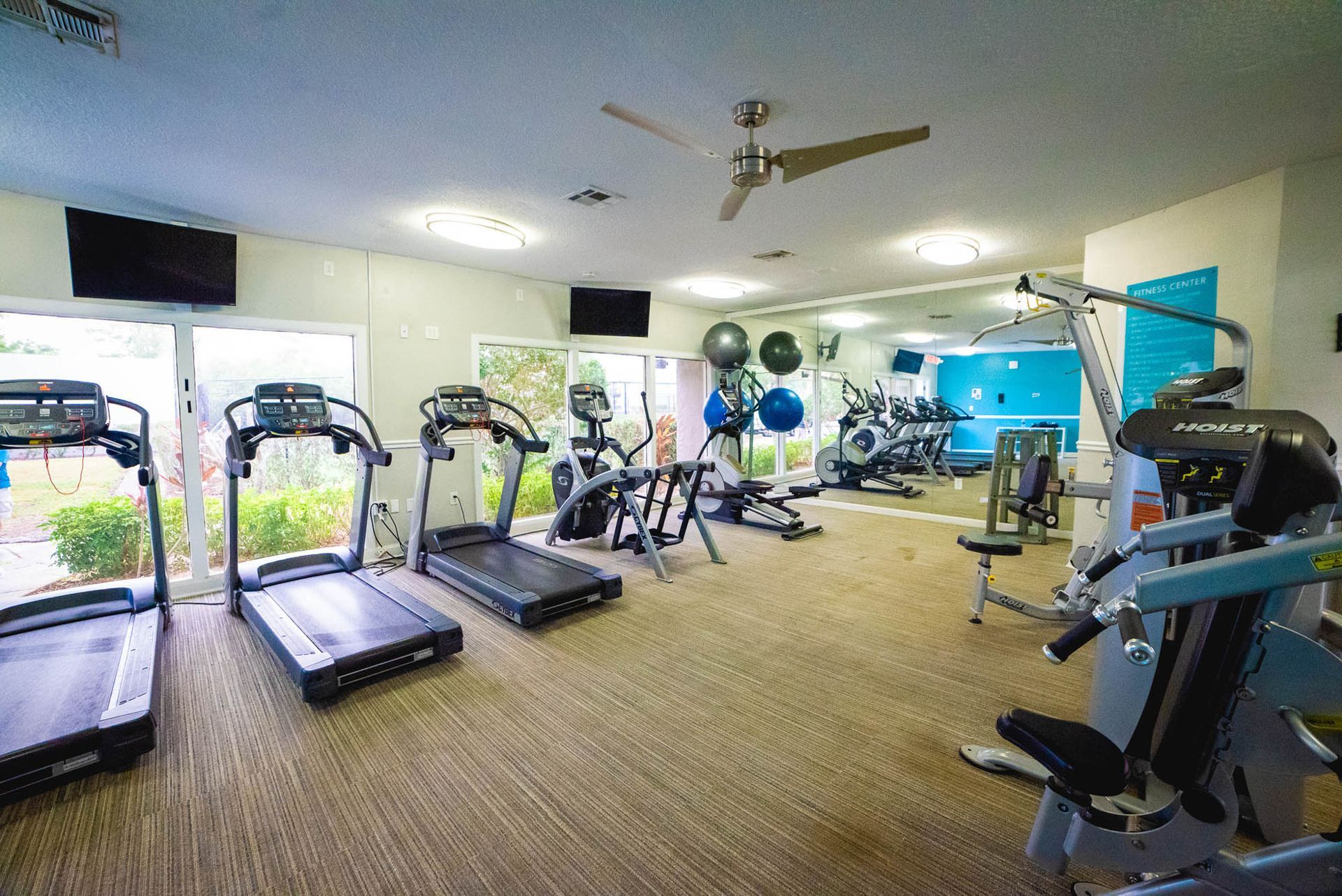 A gym with treadmills , exercise bikes , and a ceiling fan at Trellis at The Lakes.
