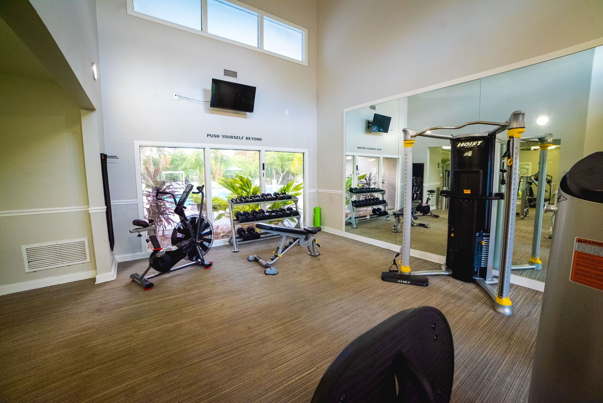 A gym with a lot of exercise equipment and a large mirror at Trellis at The Lakes.