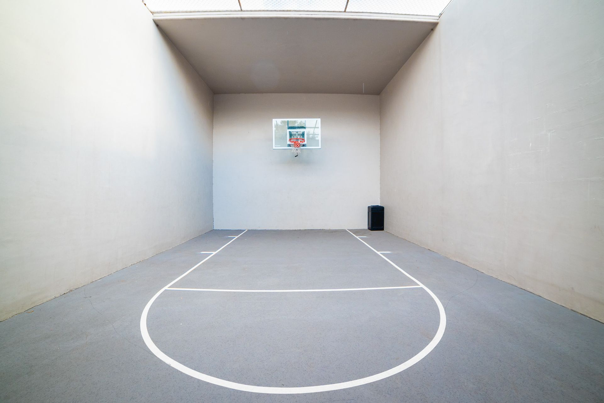 An empty basketball court with a basketball hoop on the wall at Trellis at The Lakes.