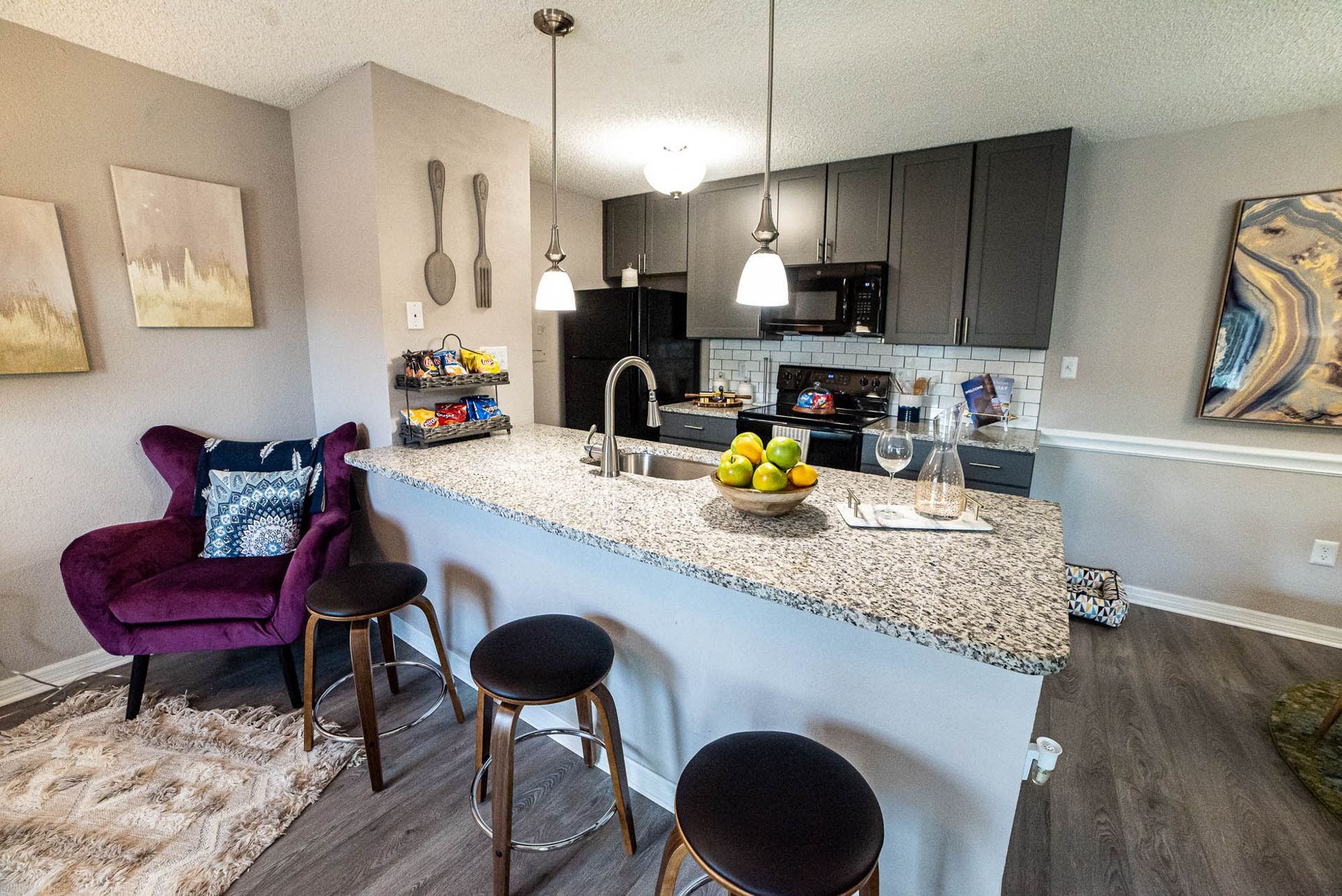A kitchen with granite counter tops and a purple chair at Trellis at The Lakes.