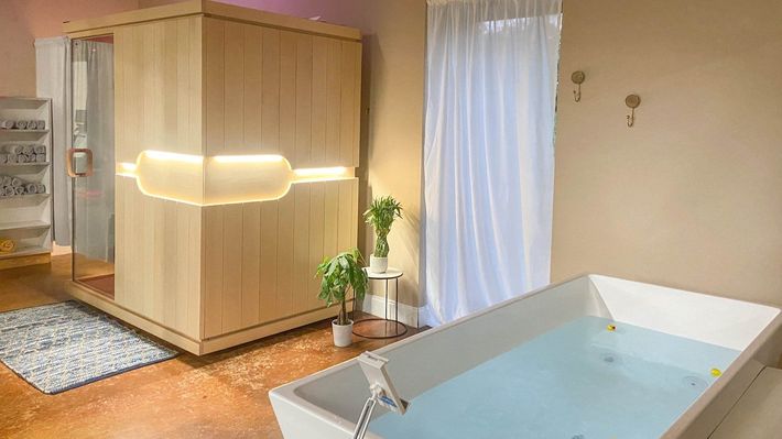 A bathroom with a sauna and a bathtub filled with water.