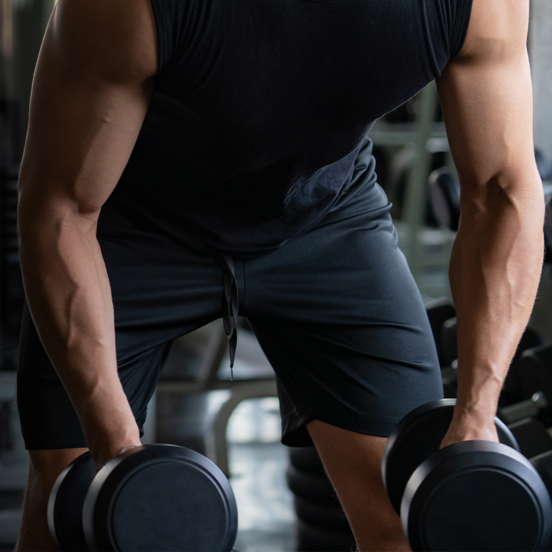 A man is lifting a pair of dumbbells in a gym