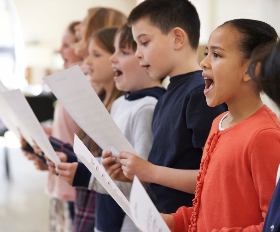 A group of children are singing together in a choir