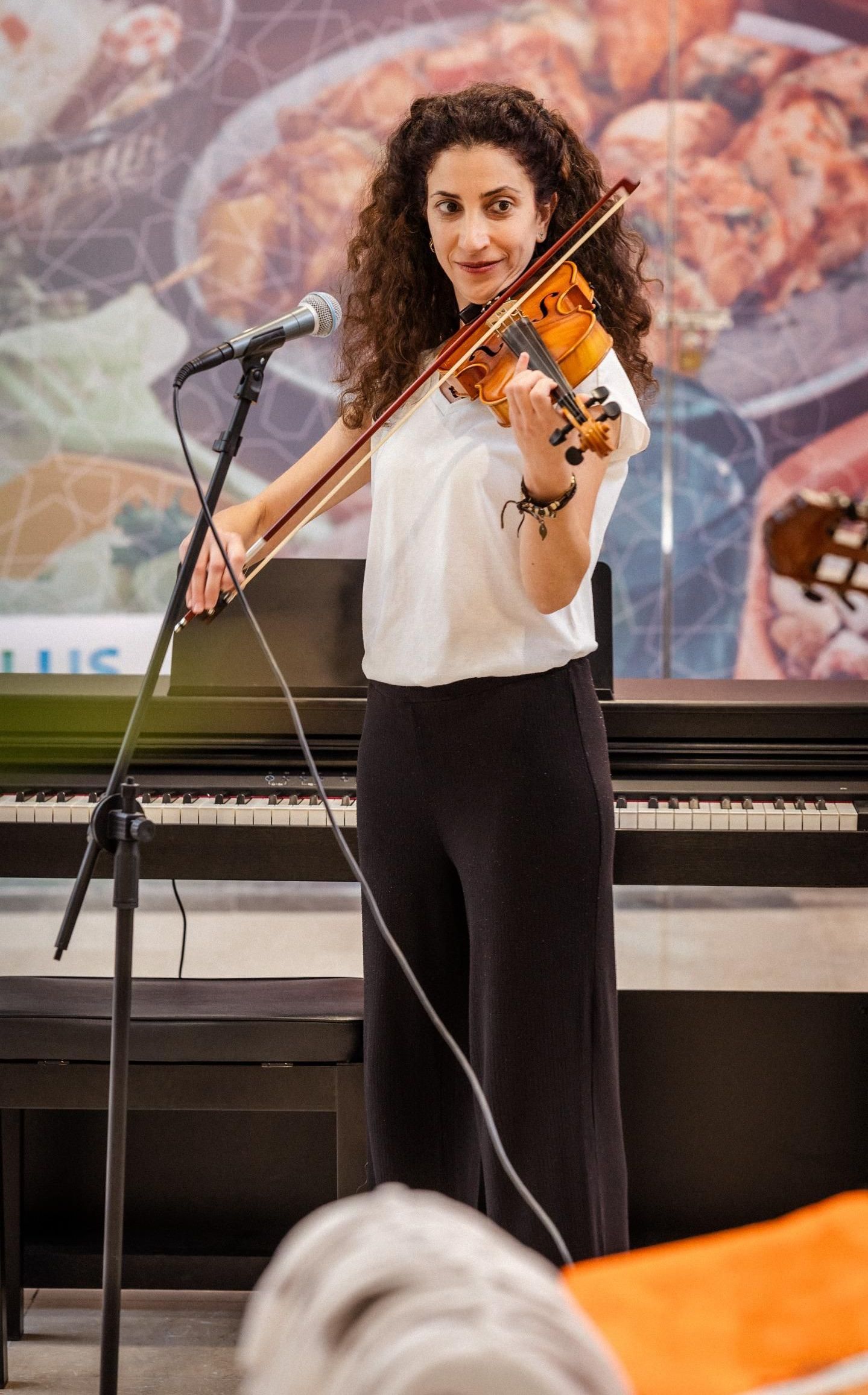 A woman is playing a violin in front of a microphone.