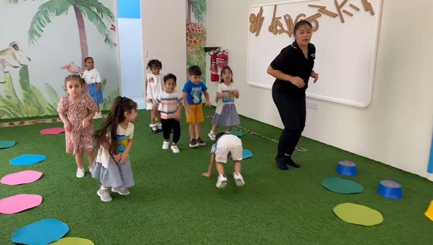 A group of children are playing in a room with a teacher.