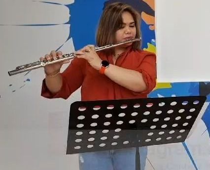 A woman is playing a flute on a stand.