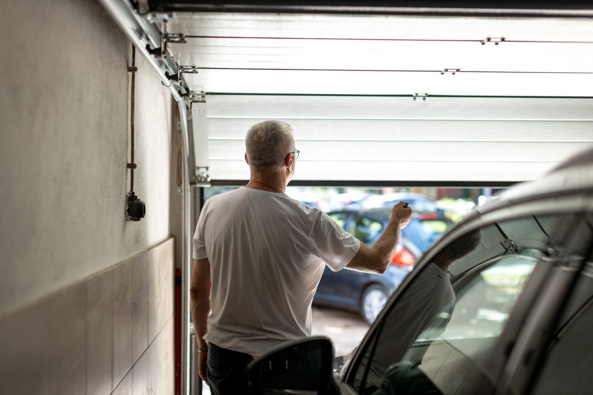 Person uses remote to open or close garage door. Person uses remote to open or close garage door.