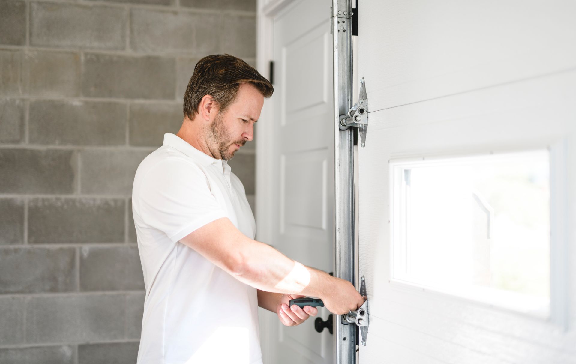 A technician is fixing a garage door. A technician is fixing a garage door.