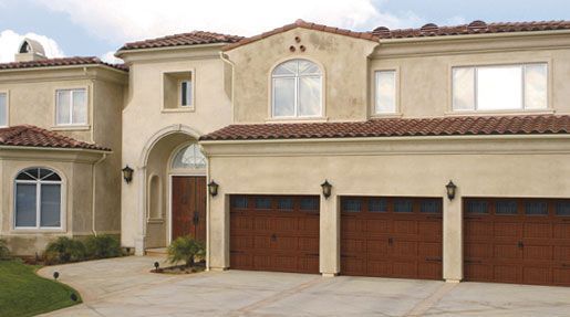 A large house with three garage doors and a tiled roof