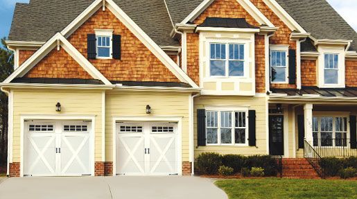 A large house with two garage doors and a brick siding