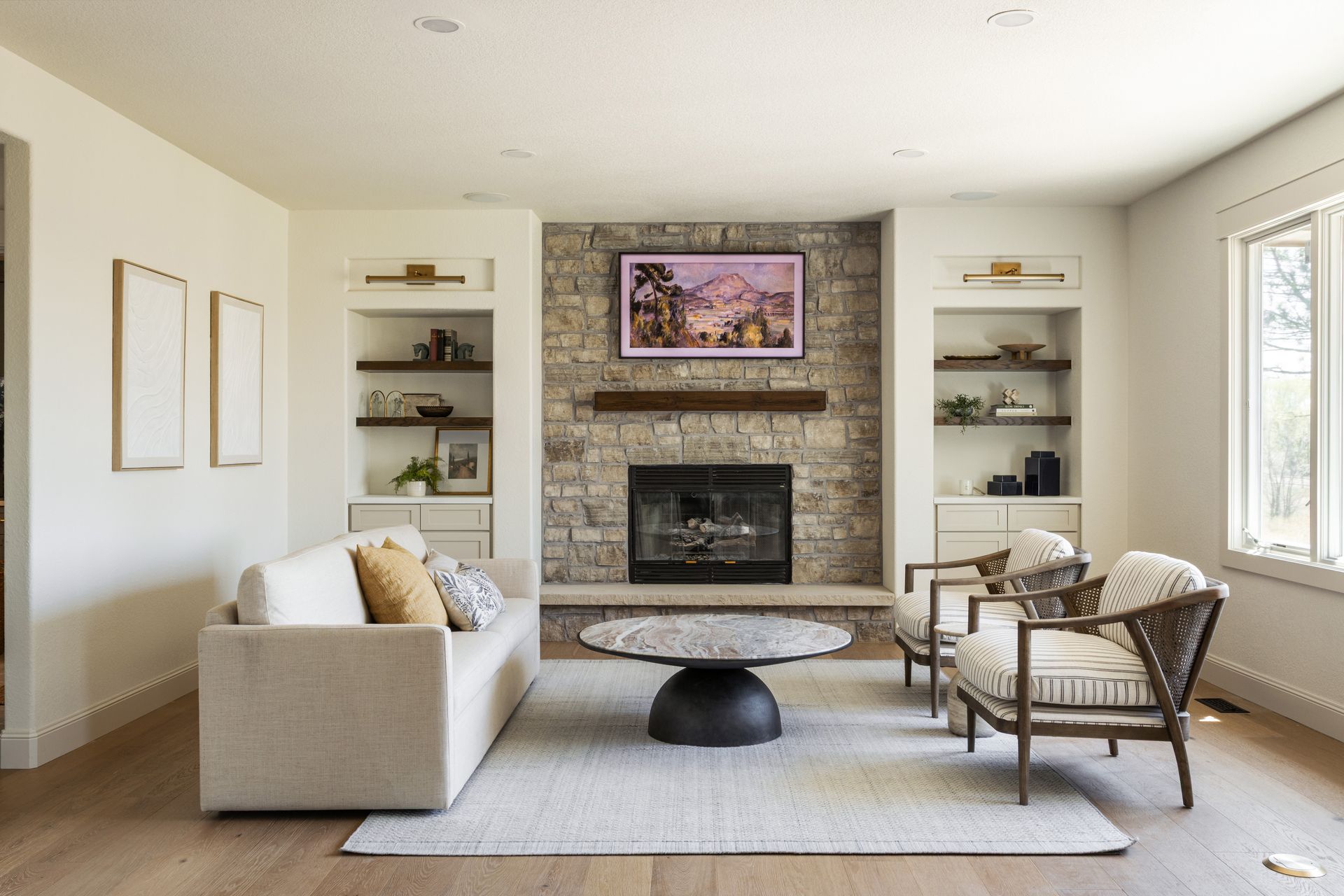 Living room with stone fireplace, TV, built-in shelves, sofa, chairs, and coffee table.