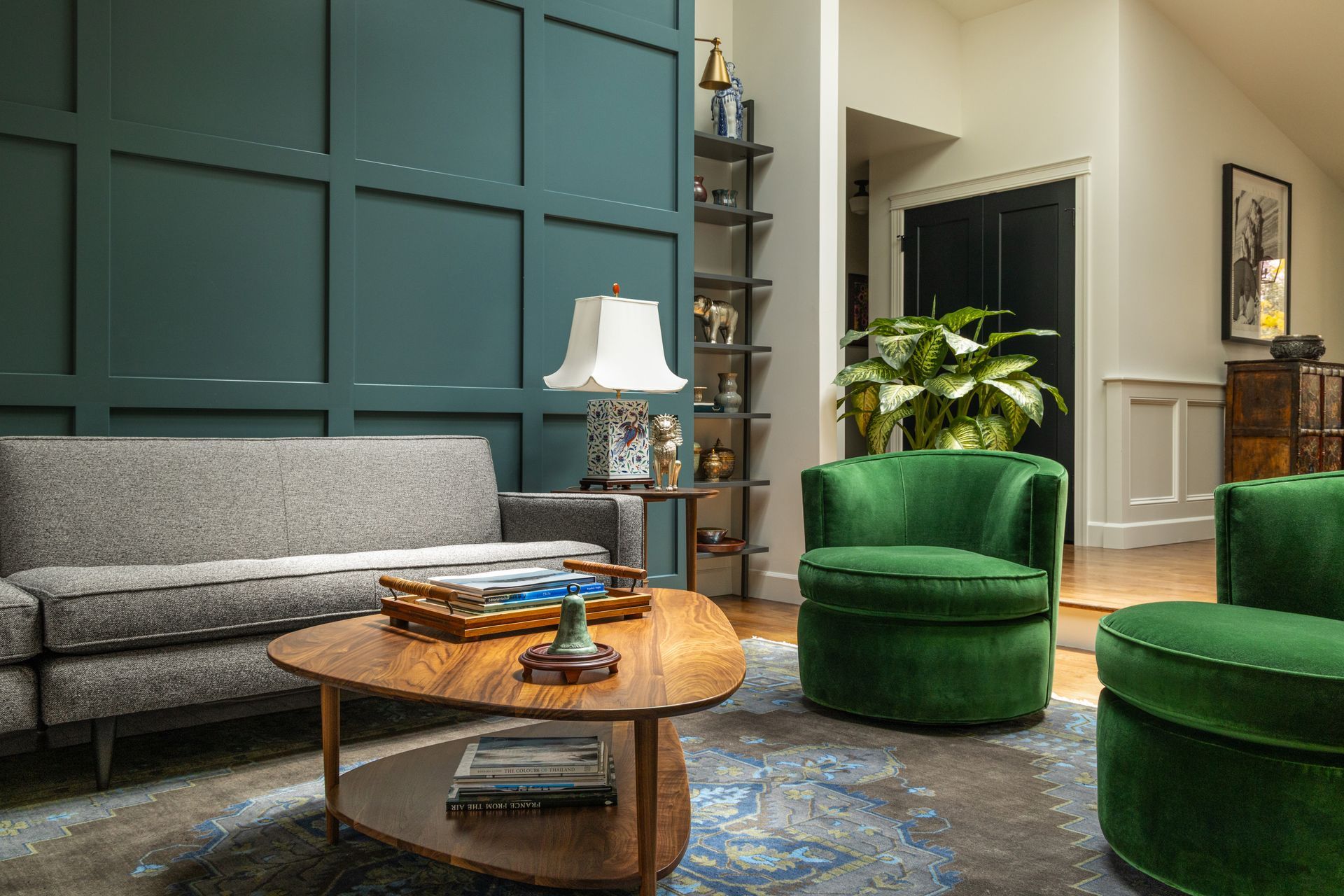 Living room with teal accent wall, gray couch, two green armchairs, and wooden coffee table.