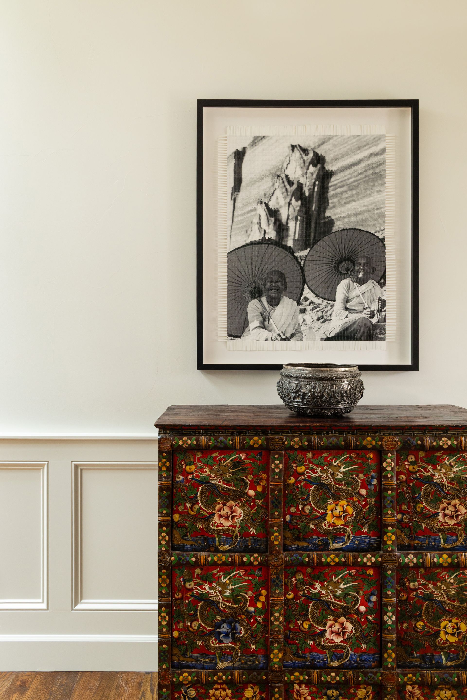 Black and white artwork of figures beneath umbrellas, above a decorative chest.