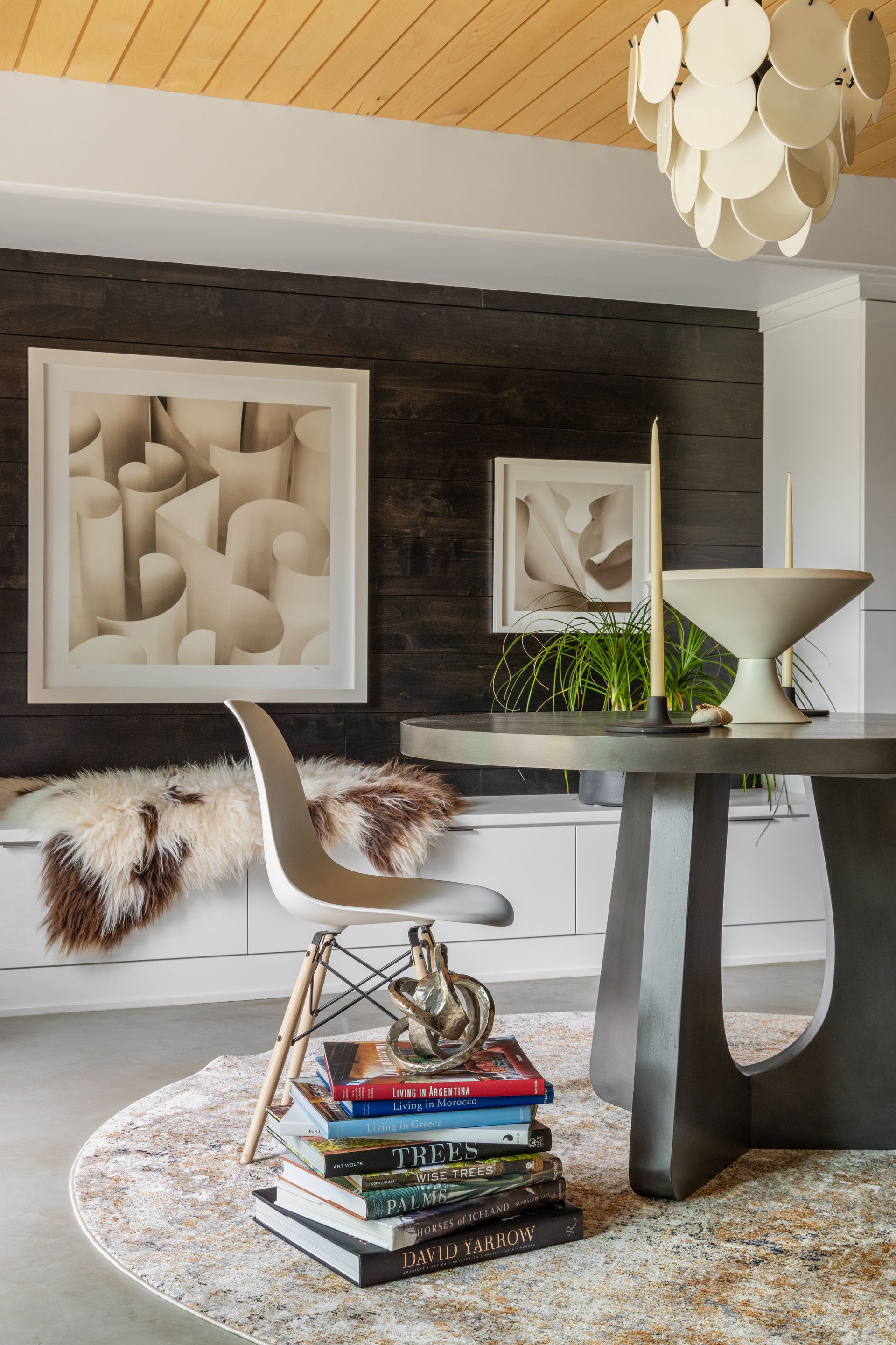 Modern interior with artwork, round table, chair, and books.