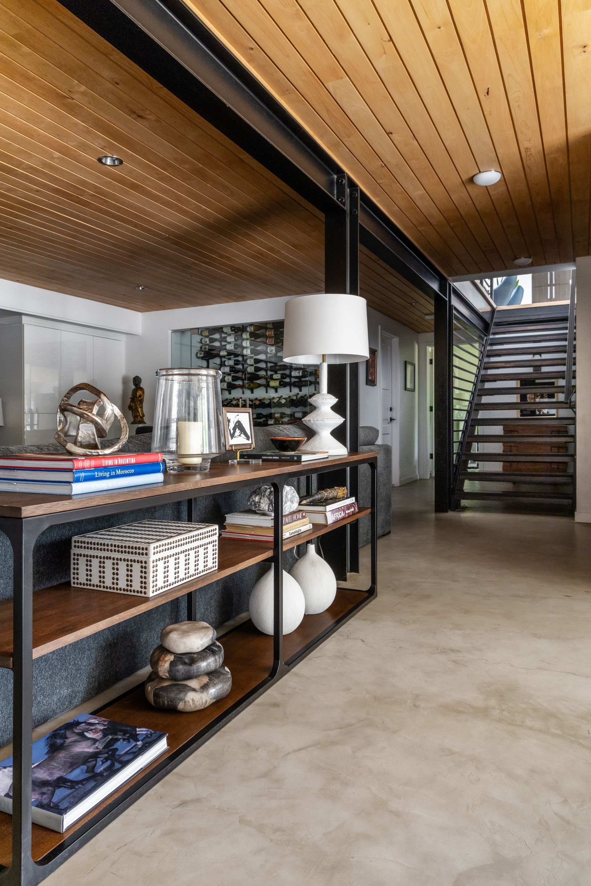 Hallway with a long wooden and steel shelf, a light-colored ceiling, and a staircase.