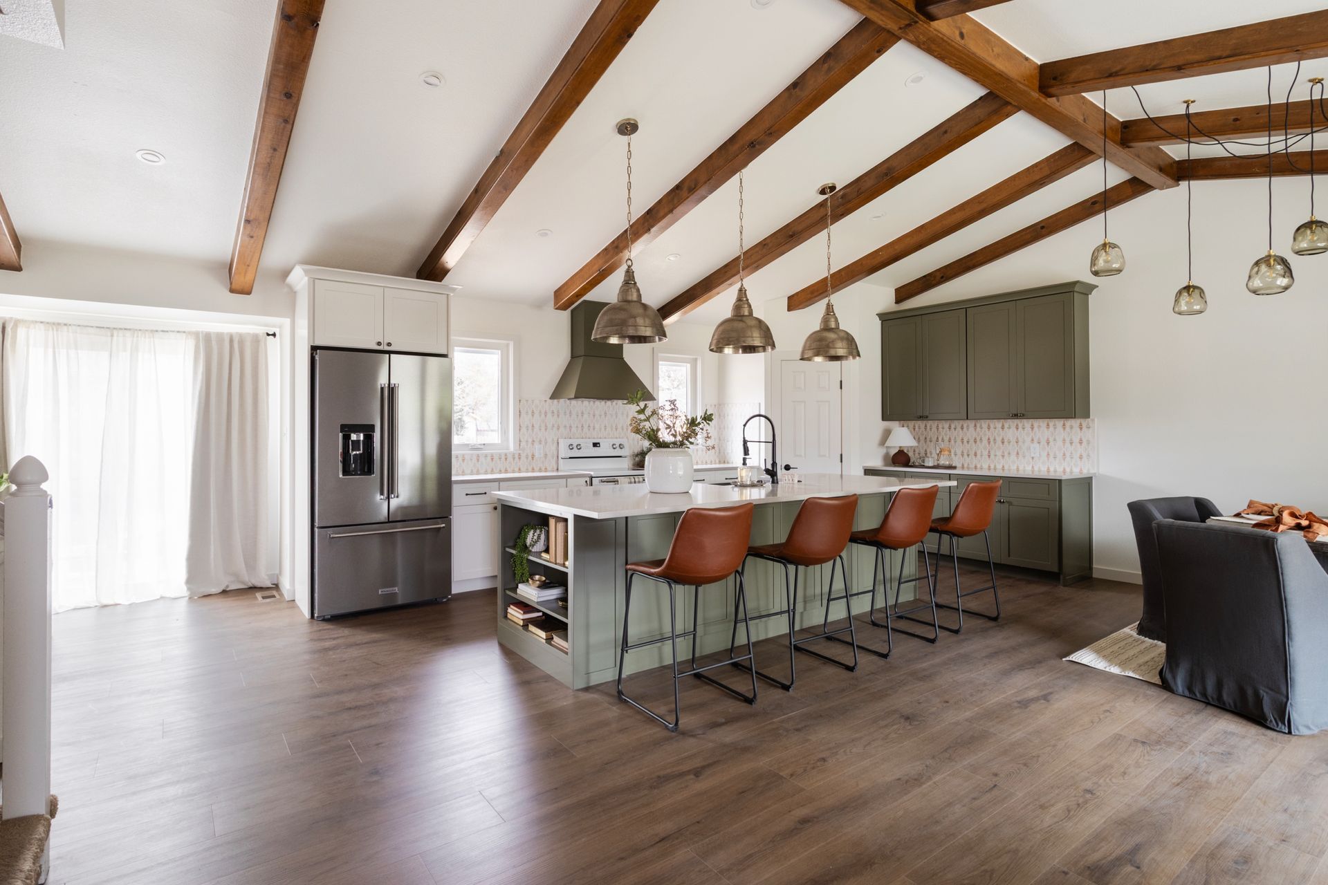 Spacious kitchen with vaulted ceiling, wood beams, island with seating, and stainless steel appliances.