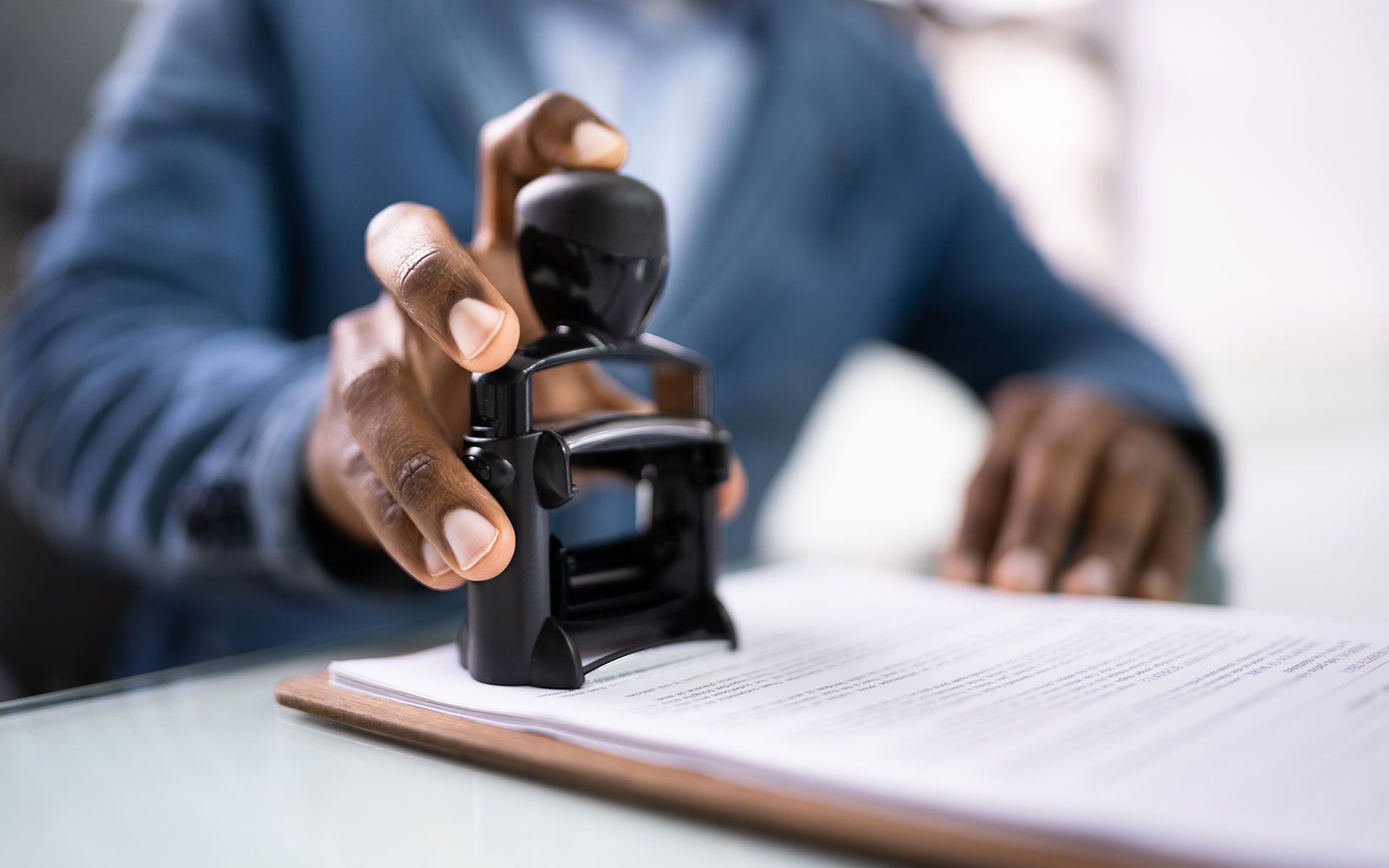 Person stamping a document with a black stamp; close-up view.