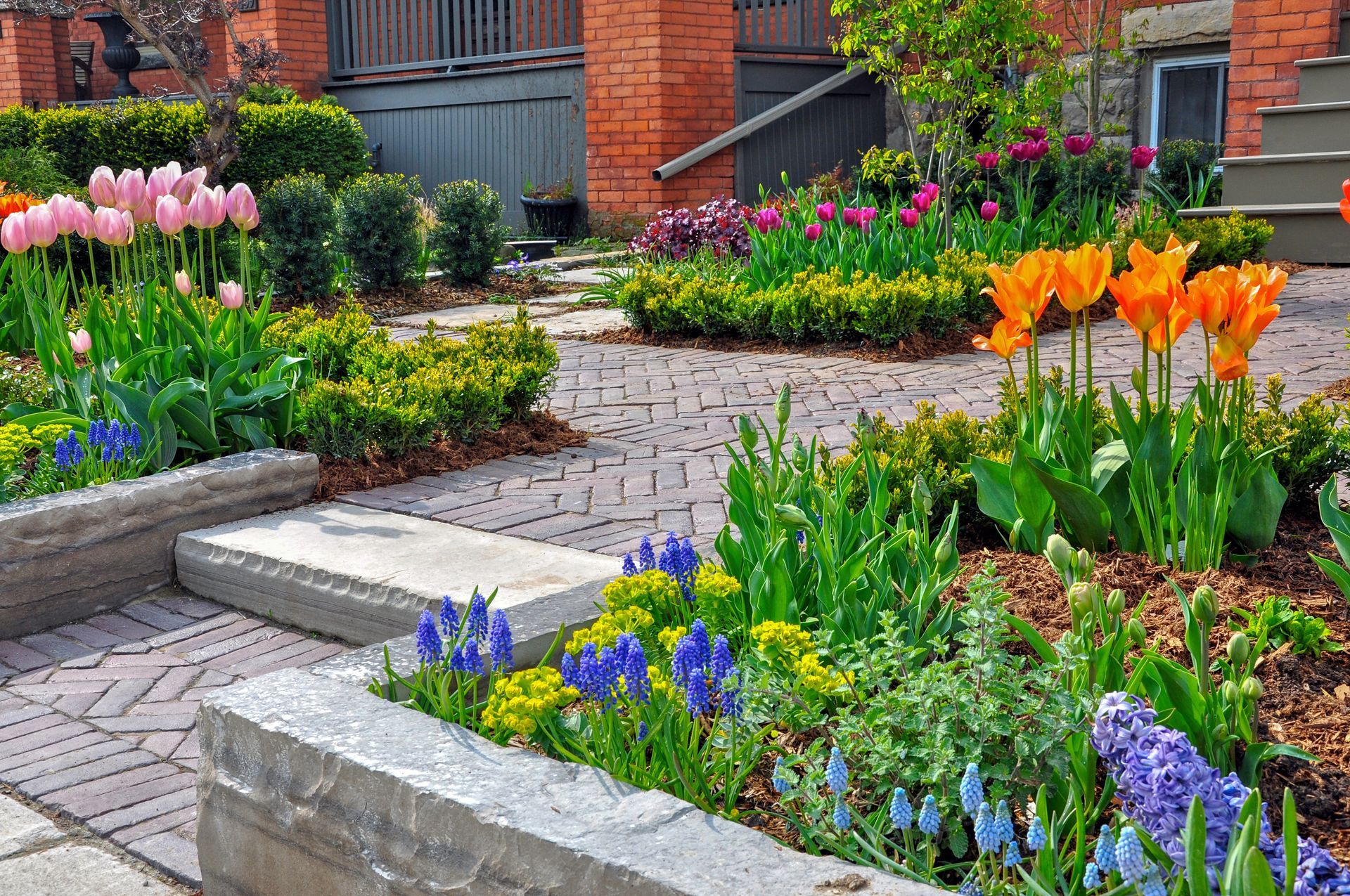 a garden with lots of flowers and brick walkway